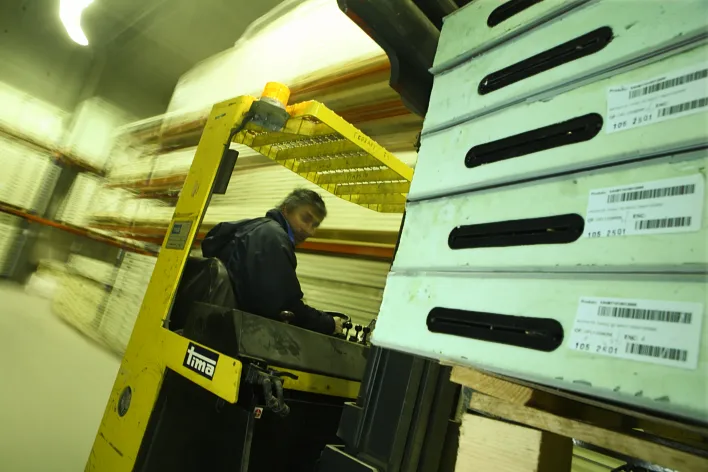 Opérateur logistique préparant l'expédition de matériel à l'aide d'un chariot élévateur dans l'entrepôt de l'usine.