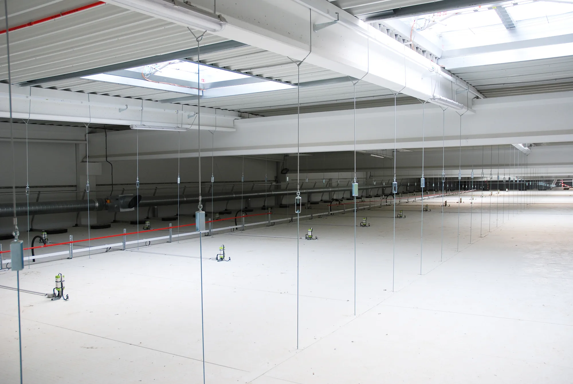Installation d'un plafond suspendu industriel en panneaux isothermes pour l'isolation d'un grand complexe de production agroalimentaire.