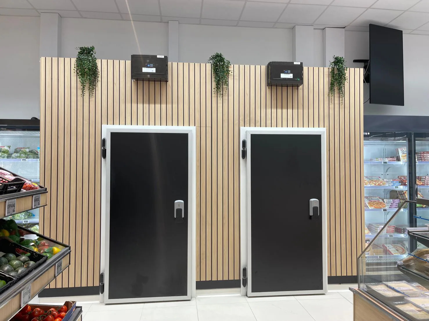 Portes isothermes noires Celtek intégrées dans l'espace de vente d'un supermarché pour le secteur du froid commercial.